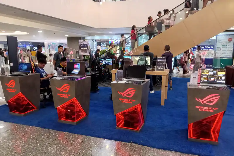 Gaming laptops on display at a tech fair in SM City Cebu with shoppers walking past
